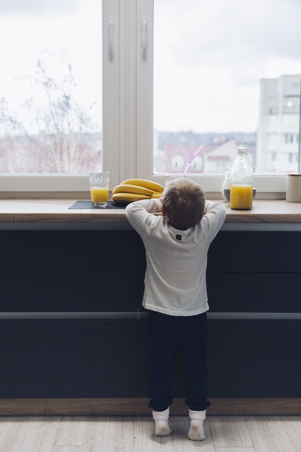 Little boy eating breakfast near a drafty window