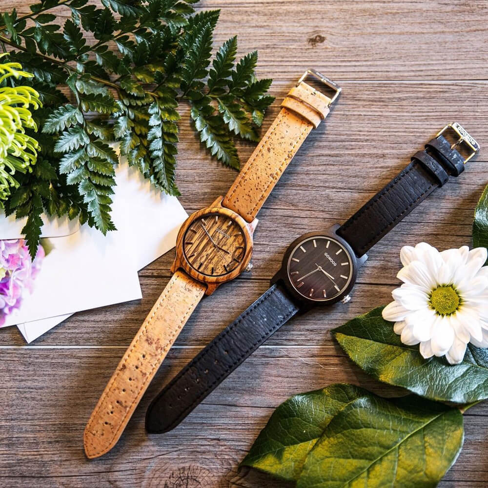 Two wooden watches with cork straps, surrounded by flowers and leaves as a great wooden gifts idea