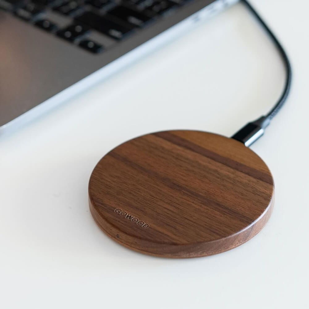 A wooden wireless charger by GOWOOD next to a laptop