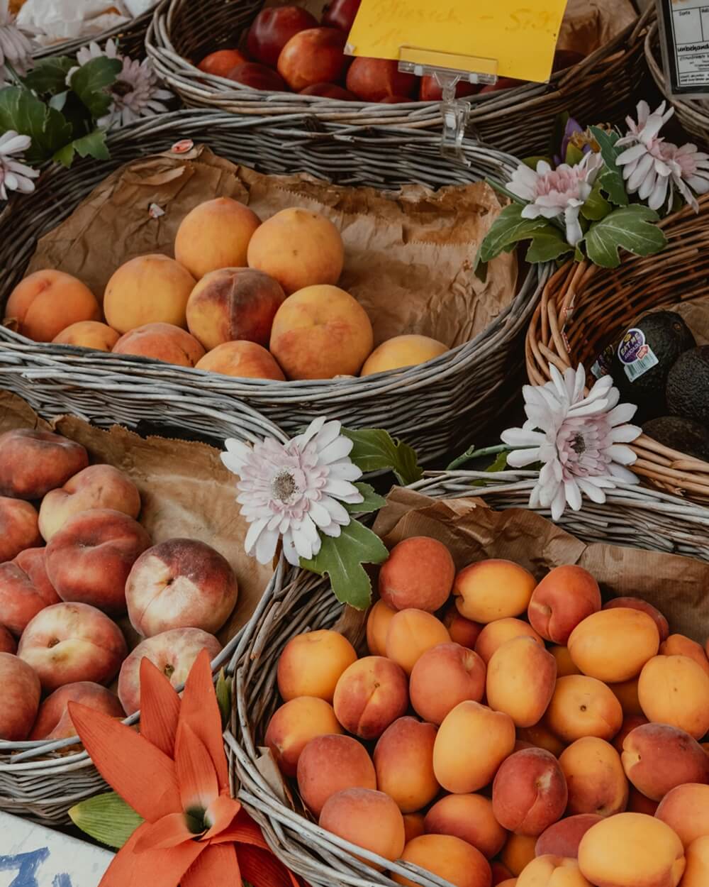 A market stall displaying fresh peaches and apricots in wicker baskets