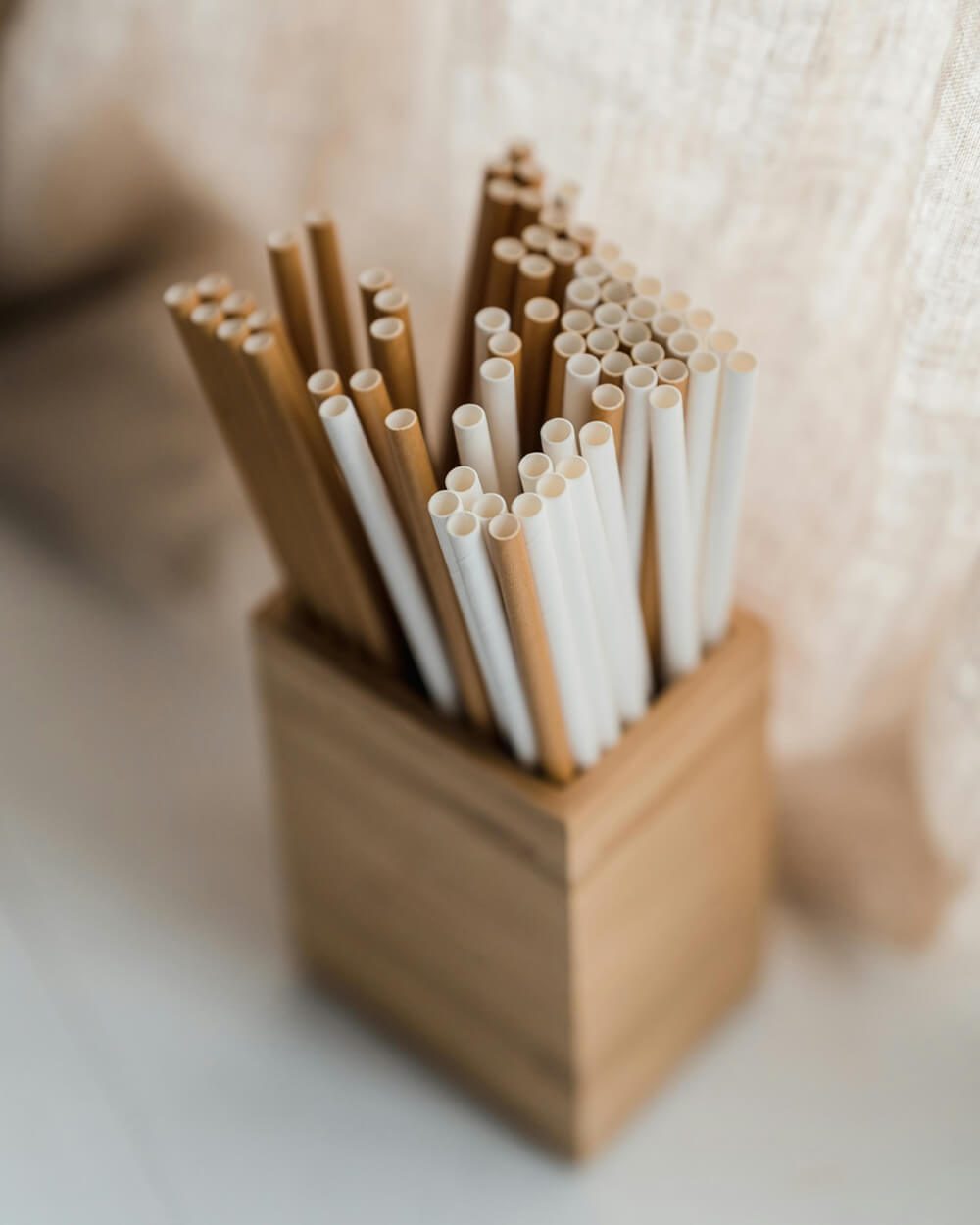 A wooden holder filled with a variety of plastic straws